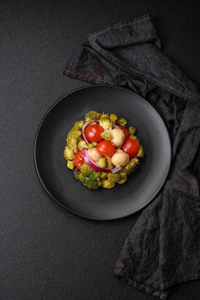 Πεντανόστιμη φρέσκια σαλάτα με μπρόκολο, ντοματίνια, μανιτάρια, κρεμμύδια, αλάτι, μπαχαρικά και βότανα σε σκούρο μπετόν φόντο - Φωτογραφία, εικόνα
