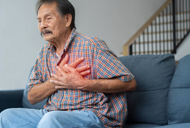 Een persoon ervaart pijn op de borst veroorzaakt door een hartaanval. Hartziekte. Angina pectoris. Het begrip ziektekostenverzekering voor ouderen. - Foto, afbeelding