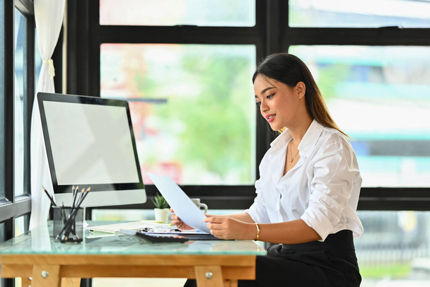 asiatico femmina dipendente lettura documenti, revisione progetto vendite rapporti in luce moderno ufficio. - Foto, immagini