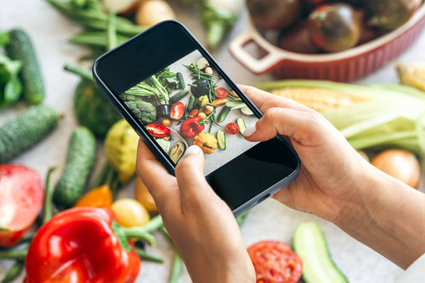 Las manos de las mujeres toman fotos de alimentos para teléfonos inteligentes de verduras, fotografía telefónica para redes sociales o blogs, dieta saludable. - Foto, imagen