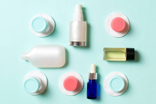 Group of small bottles for travelling on colored background. Copy space for your ideas. Flat lay composition of cosmetic products. Top view of cream containers with cotton pads. - Photo, Image