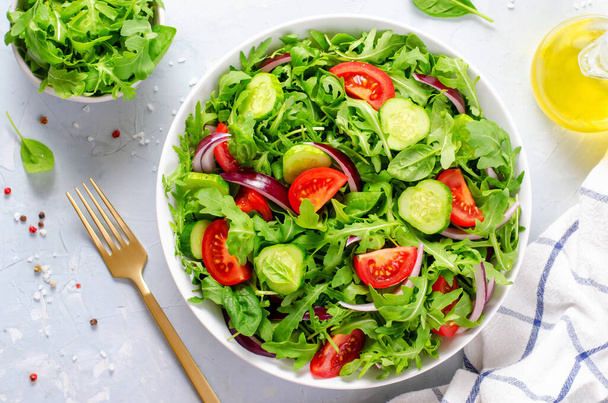 Gezonde Plantaardige Salade met Tomaten, Arugula, Komkommers en Ui, Veganistisch, Dieet Menu, Heldere achtergrond - Foto, afbeelding