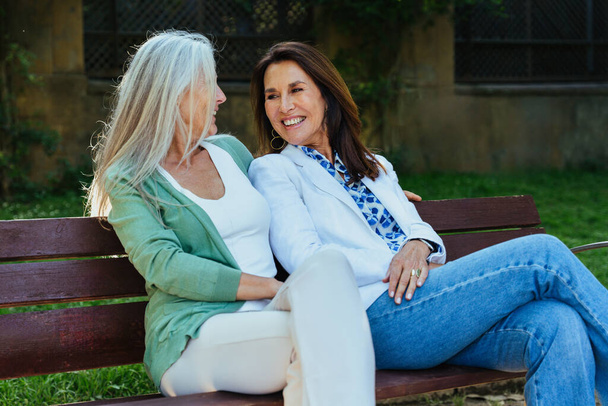 Beautiful senior women bonding outdoors in the city - Attractive cheerful mature female friends having fun, shopping and bonding, concepts about elderly lifestyle - Photo, image
