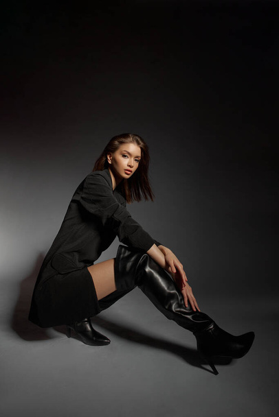 Fashionable woman in black leather boots and black jacket, portrait. Long hair, beauty, beautiful eyes - Foto, Imagen