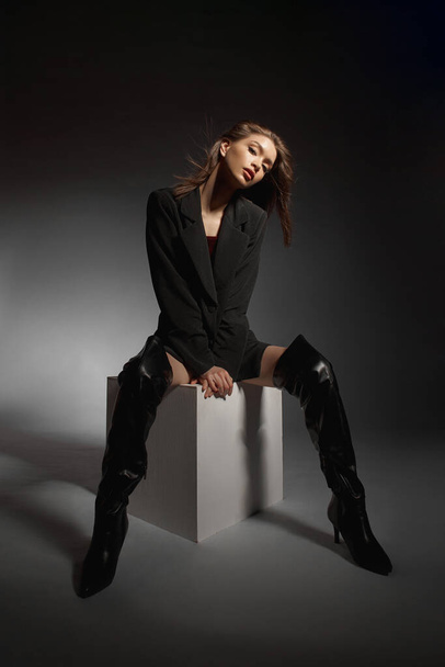 Fashionable woman in black leather boots and black jacket, portrait. Long hair, beauty, beautiful eyes - 写真・画像