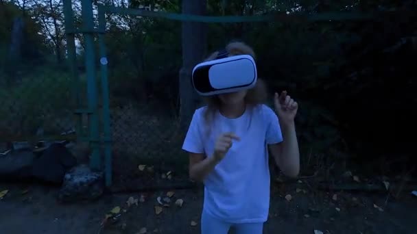 Niña en gafas de realidad virtual juega un juego de terror por la noche. Miedo juego virtual por la noche. - Imágenes, Vídeo