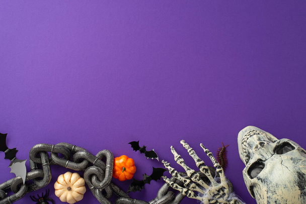 Escena de Halloween espeluznante: Vista aérea de la configuración temática, cadena de prisioneros, rastreos espeluznantes como ciempiés y araña, mano zombi esquelética, cráneo, calabazas, murciélagos contra el telón de fondo violeta, espacio para el texto - Foto, Imagen