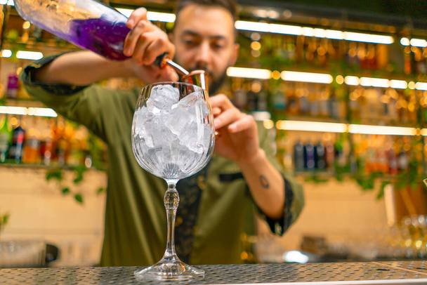 ammatillinen baarimikko luo cocktail juoma kaataa alkoholia mittalasiin baarissa - Valokuva, kuva