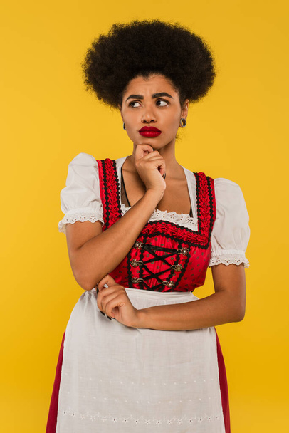 upset african american oktoberfest waitress in traditional costume looking away on yellow - Photo, Image