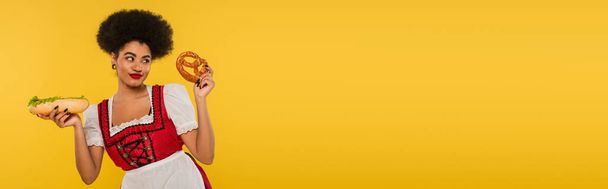 vidám afro-amerikai oktoberfest pincérnő Dirndl hot dog és perec sárga, banner - Fotó, kép