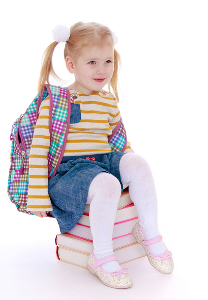 charming little schoolgirl with satchel behind him sitting on a - Φωτογραφία, εικόνα