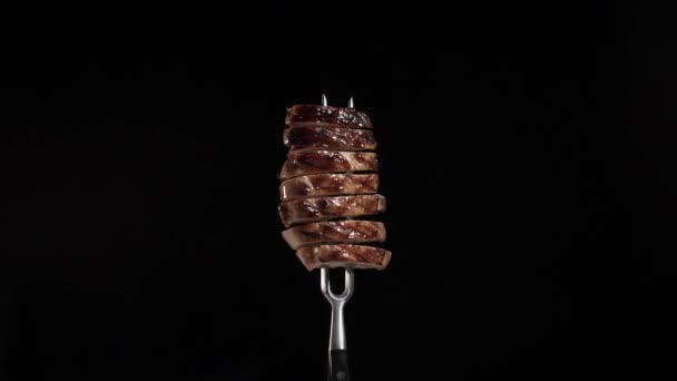 Detailní grilování steak na vidličce, rotace na černém pozadí, kouř - Záběry, video