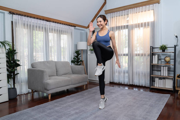 Energique et forte femme asiatique athlétique en cours d'exécution en place à sa maison. Poursuite de la forme physique et l'engagement à un mode de vie sain avec l'entraînement à domicile et la formation. Vigoureux - Photo, image