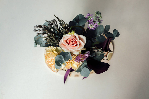 Un bouquet de fleurs dans un emballage rectangulaire sur un fond de béton gris. Bouquet de roses, branches d'eucalyptus. Fond avec des fleurs. Vue du dessus - Photo, image