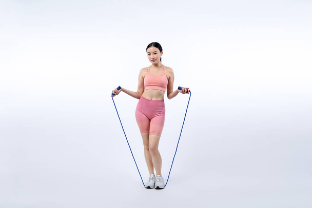 Spor giyim sektöründe genç enerjik Asyalı kadın atlıyor ya da atlıyor stüdyo çekimlerinde izole edilmiş arka planda portre pozu veriyor. Kardiyo egzersiz aleti ve sağlıklı vücut bakımı yaşam tarzı. Kuvvetli - Fotoğraf, Görsel