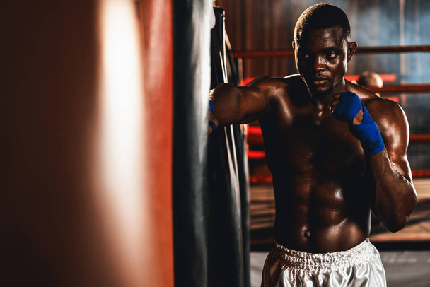 Αφρο-Αμερικανός Μαύρος μποξέρ γρονθοκόπησε τσάντα ως εξοπλισμός εκπαίδευσης τσάντα πυγμαχίας στο γυμναστήριο για τη δύναμη και την αντοχή εκπαίδευση για επαγγελματικό αγώνα πυγμαχίας. Ιμπέτους - Φωτογραφία, εικόνα