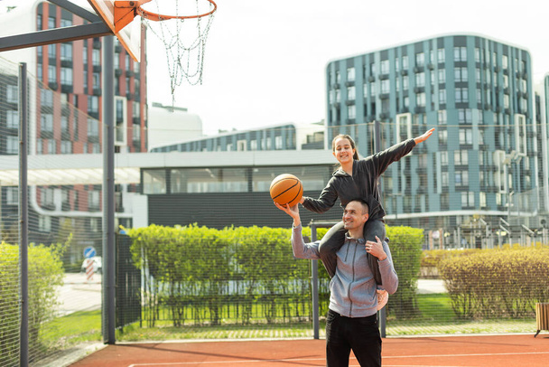 Padre e hija adolescente jugando baloncesto afuera en la corte. - Foto, imagen
