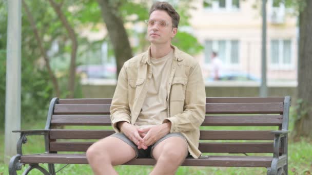 Lässiger junger Mann sitzt mit Rückenschmerzen im Freien - Filmmaterial, Video