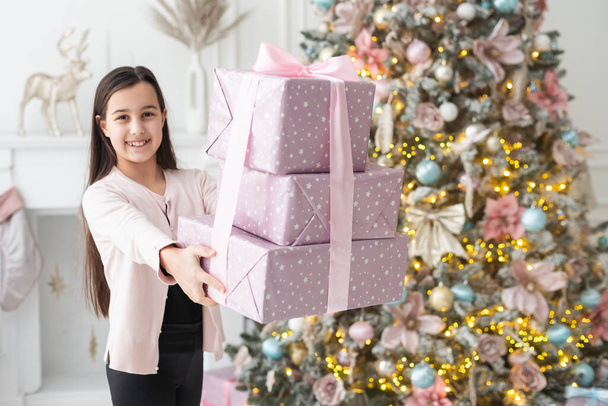 Χαρούμενο μικρό χαμογελαστό κορίτσι με χριστουγεννιάτικο κουτί δώρου. - Φωτογραφία, εικόνα