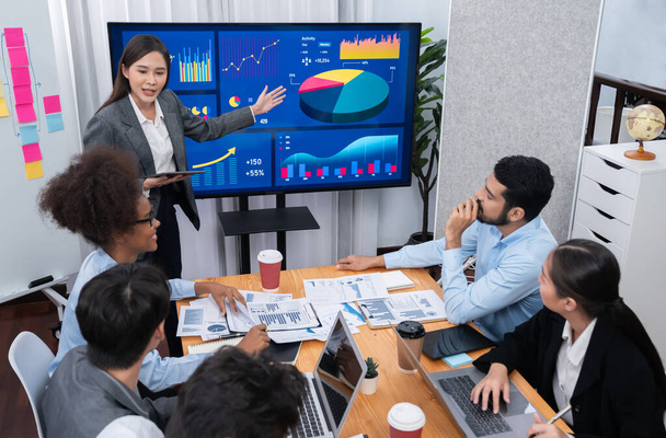 Młoda azjatycka bizneswoman prezentująca pulpit analizy danych na ekranie telewizora w nowoczesnym spotkaniu. Prezentacja biznesowa z grupą ludzi biznesu w sali konferencyjnej. Zgoda - Zdjęcie, obraz