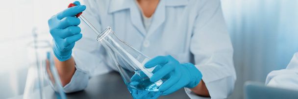 Wetenschapper voert chemisch experiment in medisch laboratorium, zorgvuldig druppel precieze hoeveelheid vloeistof uit pipet in reageerbuis voor vaccin drug of antibiotica ontwikkeling. Neoterisch - Foto, afbeelding