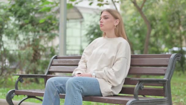 Случайная молодая женщина сидит на улице с болью в шее - Кадры, видео