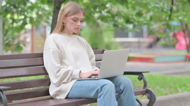 Mujer joven con dolor de cuello trabajando en el ordenador portátil al aire libre - Imágenes, Vídeo