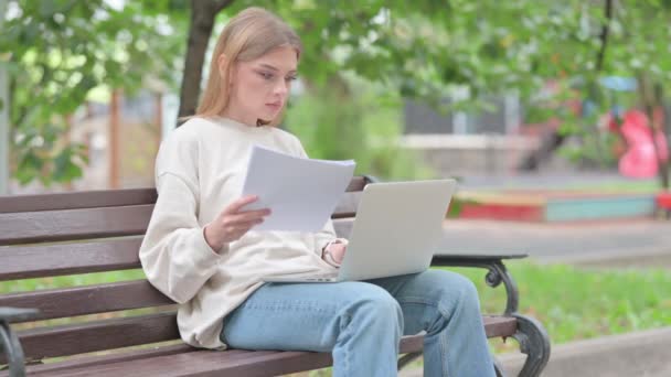 Mujer joven se siente molesto mientras lee el contrato y el uso de la computadora portátil al aire libre - Metraje, vídeo