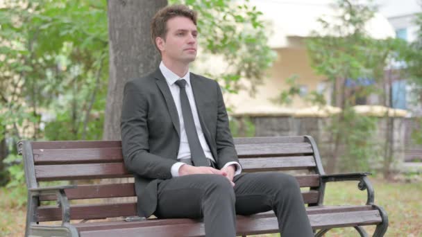 Joven hombre de negocios sentado al aire libre con dolor de espalda - Metraje, vídeo