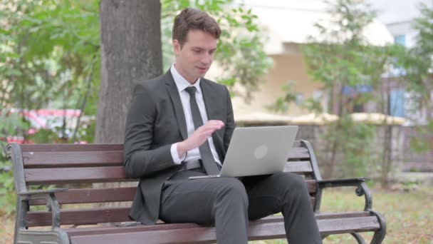 Онлайн видео чат молодого бизнесмена на ноутбуке на открытом воздухе - Кадры, видео