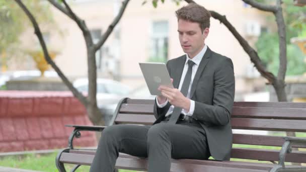 ベンチに座っている間,タブレットで損失を被るビジネスマン - 映像、動画