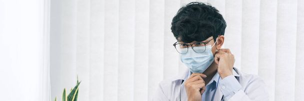 aziatische man arts het dragen van een masker in zijn kantoor. - Foto, afbeelding