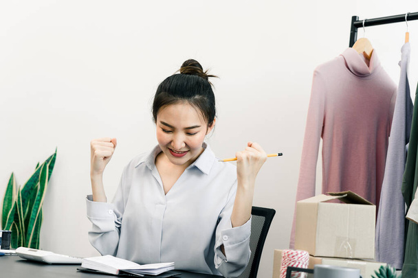 Junge asiatische Unternehmer freuen sich, wenn sie ihre Kleidung zielgerichtet verkaufen. - Foto, Bild