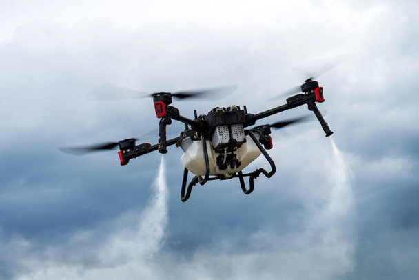 Nowoczesne technologie w rolnictwie. Przemysłowy dron przelatuje nad zielonym polem i spryskuje użytecznymi pestycydami w celu zwiększenia wydajności i zniszczenia szkodliwych owadów. zwiększenie wydajności - Zdjęcie, obraz