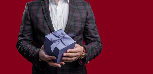 cropped view of man with proposal gift isolated on red background with copy space. man hold proposal gift in studio. man with proposal gift. photo of man holding proposal gift. - Foto, Imagem