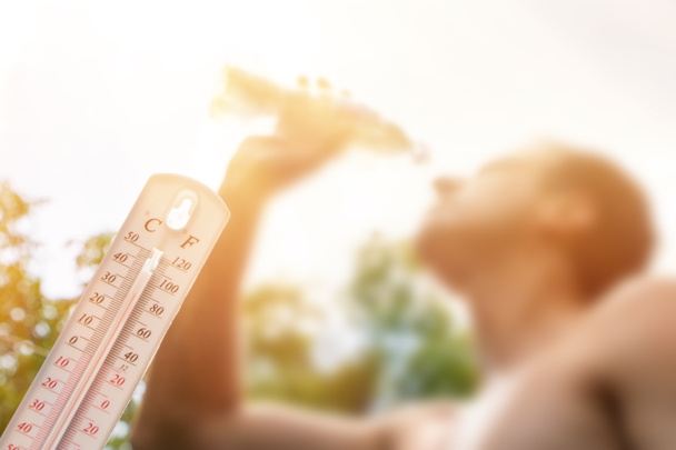 Muž pitná voda v extrémním teple, Teploměr v letním dni ukazuje nebo indikovat vysokou teplotu stupně se sluncem v pozadí. - Fotografie, Obrázek