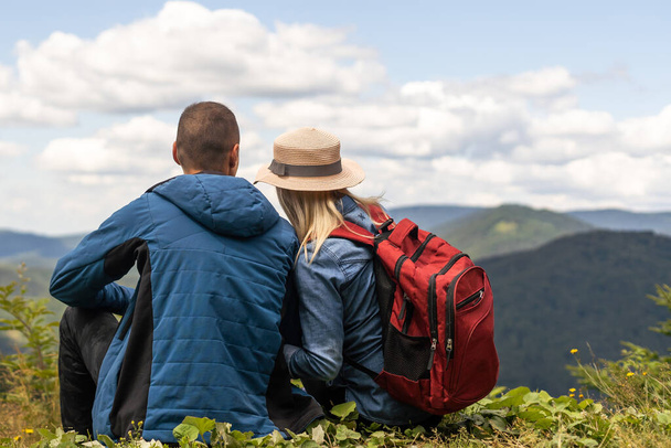 Hikers with backpacks relaxing on top of a mountain and enjoying the view. - Photo, image