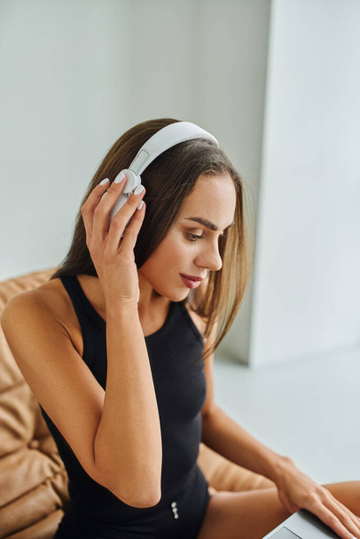 piękna i brunetka kobieta z długimi włosami słuchanie muzyki w bezprzewodowych słuchawkach w domu - Zdjęcie, obraz