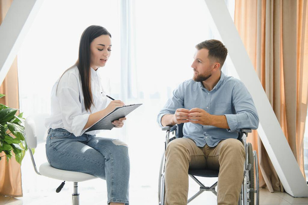Portrait of female psychiatrist interviewing handicapped man during therapy session, copy space - Foto, Bild