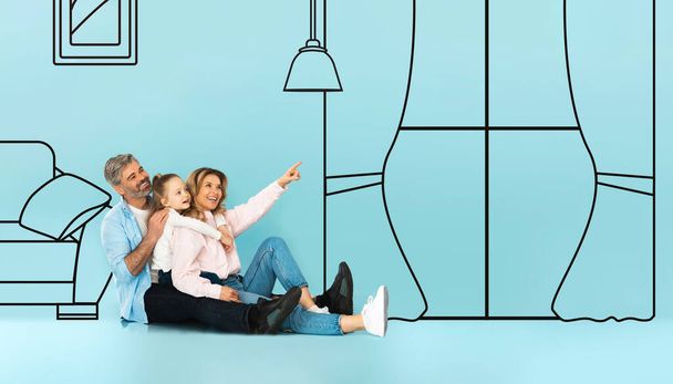 Positive european family sit on floor, point finger at window, isolated on blue studio background, with abstract drawn furniture in living room interior, panorama. Buy real estate, ad, offer - Photo, Image