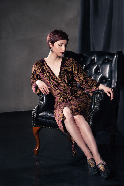 Beautiful woman wearing short dress sitting in  armchair - Foto, Imagen