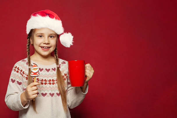 Karácsonyi gyerek. Boldog aranyos gyermek lány Mikulás Xmas dring és az élelmiszer piros banner háttér - Fotó, kép