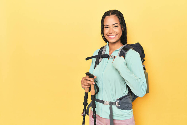 Indonesian woman with hiking gear on yellow person pointing by hand to a shirt copy space, proud and confident - Photo, Image