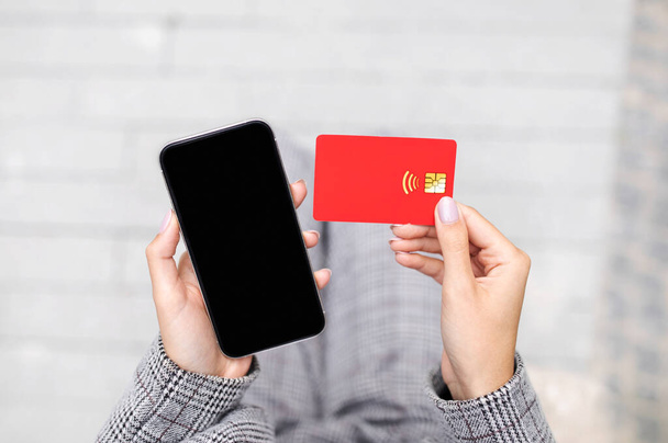Cashback για τις επιχειρήσεις. Κλείσιμο της πιστωτικής κάρτας και Smartphone με κενή μαύρη οθόνη σε χέρια επιχειρηματία Εξωτερική, κορυφαία άποψη. Lady Πληρωμές Αγορές σε απευθείας σύνδεση στην εφαρμογή τηλεφώνου. Κινητή τράπεζα - Φωτογραφία, εικόνα