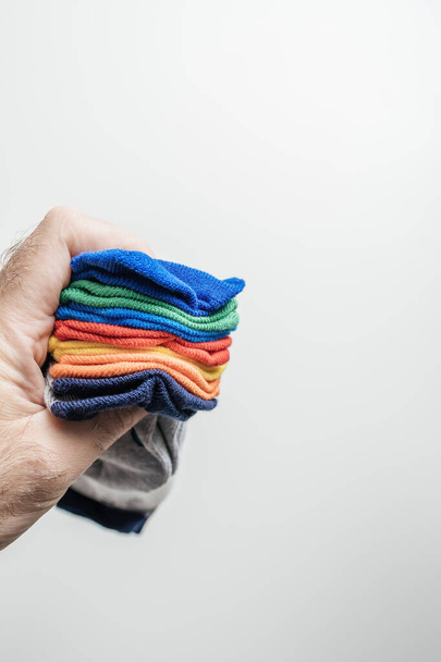 Männliche Hand schmiegt zärtlich ein Bündel lebendiger, sorgfältig organisierter Socken, jede Farbe sorgfältig für einen Wochentag bestimmt - Foto, Bild