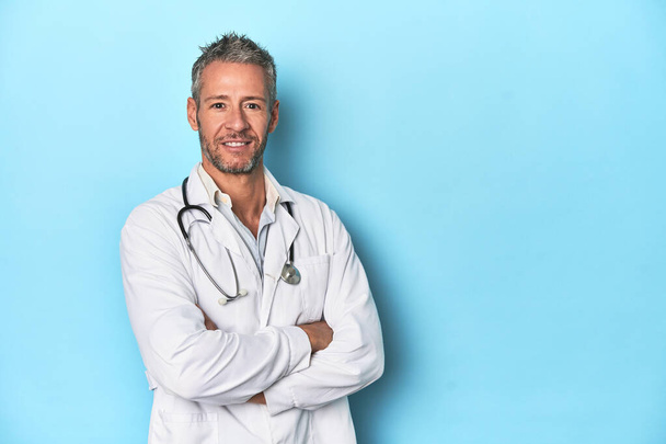 Caucasian mid-aged male doctor on a blue studio background - Photo, Image
