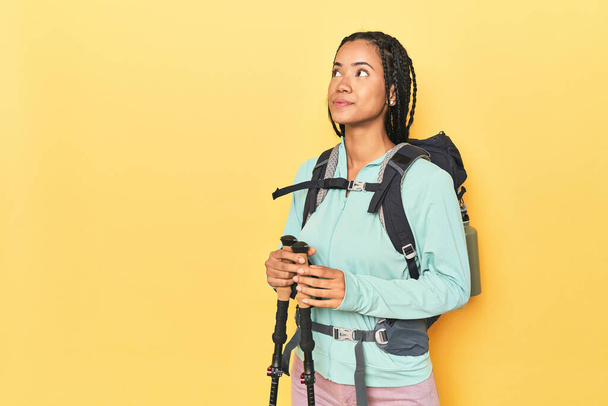 Indonesian woman with hiking gear on yellow dreaming of achieving goals and purposes - Photo, Image