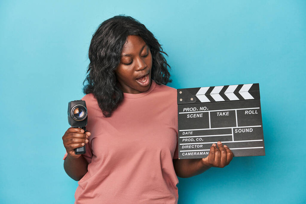 Creative curvy woman with film camera and clapperboard - Photo, Image