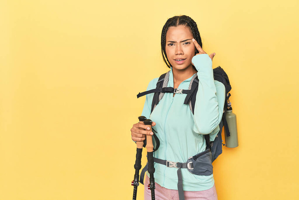 Indonesian woman with hiking gear on yellow showing a disappointment gesture with forefinger. - Photo, Image