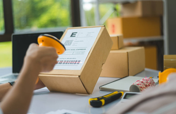 online small business owner scans a barcode-labeled parcel with a barcode scanner to verify a customer's order before it is delivered to the customer. - Photo, Image